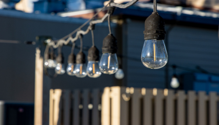 Vintage-style light bulbs hanging up at an outdoor event space in the daytime