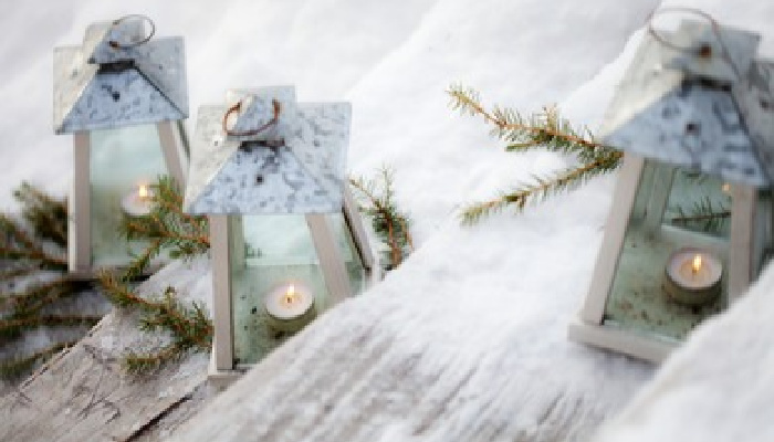Beautiful flickering candles in lanterns christmas decoration in snow