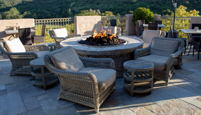 Chairs and side tables around fire pit in outdoor living space for gathering